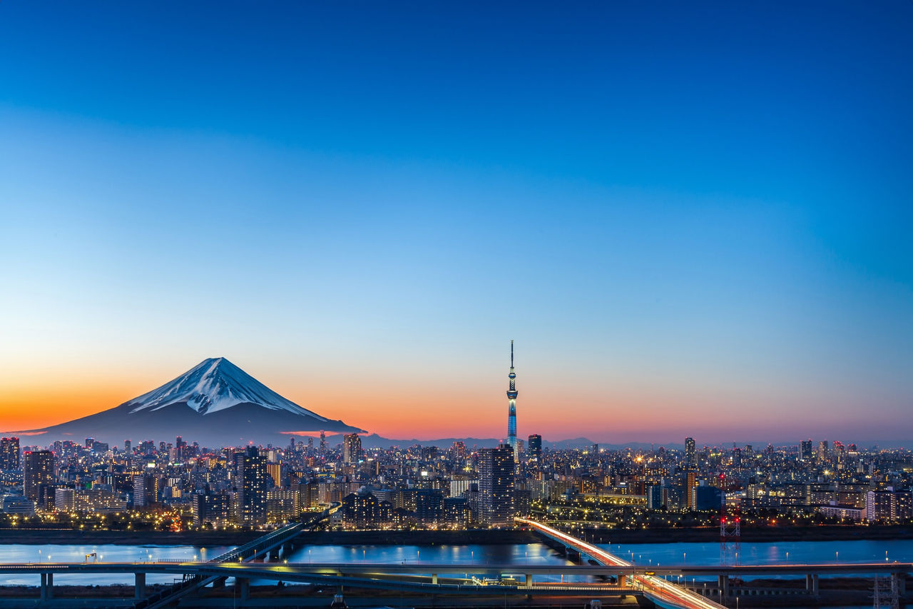 Urban sunset view with high rise buildings, and Mount Fuji, Tokyo Japan. Digitally generated image.